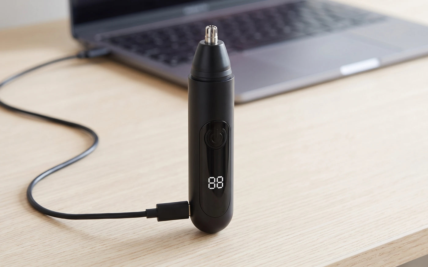 The trimmer upright on a desk with a USB-C cable plugged into the base
